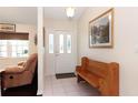 Bright foyer featuring tile flooring, a wood bench, and a door with decorative glass inserts at 4723 Saint Andrews Arc, Leesburg, FL 34748