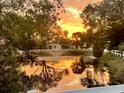 Scenic sunset view of a tranquil pond with a fountain, surrounded by lush trees and a white fence at 501 Santa Fe Rd, Tavares, FL 32778