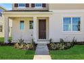 Inviting front entrance with a dark brown door, manicured lawn, and decorative landscaping at 5173 Waypointe Blvd, Apopka, FL 32712