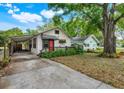 Charming home featuring a red front door, awning, driveway, and mature landscaping at 545 W Cummings St, Lake Alfred, FL 33850