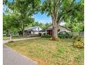 View of the home with a mature tree, landscaping, and a glimpse of the neighbor's house at 545 W Cummings St, Lake Alfred, FL 33850