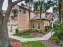 Charming two-story townhouse featuring a stucco facade, tile roof, balcony, and mature palm trees enhancing curb appeal at 602 Camino Real Blvd # 602, Howey In The Hills, FL 34737