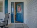 Welcoming blue front door with decorative glass and sidelight, complemented by a cozy chair at 1010 Ventura Dr, The Villages, FL 32159