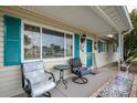 Inviting front porch with cozy seating, featuring teal shutters and a charming front door with a wreath accent at 10689 Se 174Th Loop, Summerfield, FL 34491