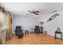 Bright living room with laminate floors, a ceiling fan, comfortable seating, and natural light from a large window at 10689 Se 174Th Loop, Summerfield, FL 34491