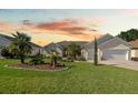 Charming single-story home with manicured lawn, brick driveway, and lush landscaping, complemented by a serene sunset backdrop at 11860 Se 179Th St, Summerfield, FL 34491