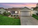 Charming single-story home with well-manicured lawn, attached two-car garage, and a screened in porch at dusk at 1307 Galindo Pl, The Villages, FL 32159