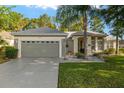 Charming single-story home with a well-manicured lawn, a gray two-car garage, and a lush palm tree in the front yard at 13190 Se 93Rd Cir, Summerfield, FL 34491