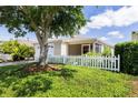 Well-maintained home with a white picket fence, lush green lawn, mature shade tree, and tidy landscaping at 1667 Osprey Ave, The Villages, FL 32162