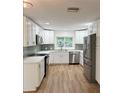 Modern kitchen featuring white cabinetry, stainless steel appliances, quartz countertops and wood look flooring at 1765 Hilltop Dr, Mount Dora, FL 32757