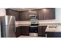 Modern kitchen featuring stainless steel appliances, granite countertops, and dark wood cabinets at 27 Perch Dr, Kissimmee, FL 34759