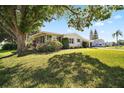 Inviting home exterior featuring a sunroom, lush lawn, mature trees offering shade, and a well-kept garden at 3209 Manatee Rd, Tavares, FL 32778