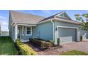Charming home featuring manicured landscaping, brick-paved driveway, and a side view of a serene lake at 3256 Canna Lily Pl, Clermont, FL 34711