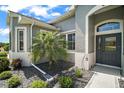 Close-up of the home's entryway showcasing a well landscaped garden and a decorative front door with unique glass detailing at 5557 Freeport Dr, Tavares, FL 32778