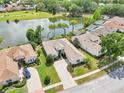 An aerial view showing a single-story home, lush lawns, mature trees, and a tranquil lake with golf course at 8043 Pine Hollow Dr, Mount Dora, FL 32757