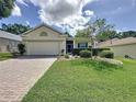 Charming single-story home features a brick driveway and meticulously landscaped front yard, with attached two-car garage at 860 Wolf Creek St, Clermont, FL 34711