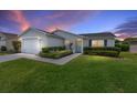 Charming single-story home with well-maintained landscaping and an attached garage at dusk at 870 Danforth Ct, The Villages, FL 32162