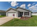 Charming single-story home with a two-car garage, landscaped front yard, and neighborhood sign at 12054 Ne 51St Cir, Oxford, FL 34484