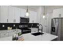 Modern kitchen featuring white cabinets, stainless steel appliances, a kitchen island with a black faucet, and pendant lighting at 13524 Sw 89 St, Dunnellon, FL 34432