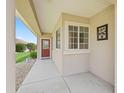 Inviting covered front porch featuring decorative windows, front door, and rock landscaping at 14235 Se 85Th Ave, Summerfield, FL 34491