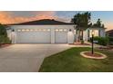 Charming home featuring a two-car garage, well-manicured lawn, and beautiful landscaping at 1502 Blueberry Way, The Villages, FL 32162