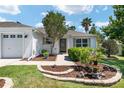 Inviting home exterior with well-maintained landscaping, including a stone-lined flower bed at 1502 Blueberry Way, The Villages, FL 32162
