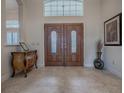 Inviting foyer with decorative table, tile flooring and beautiful wood double doors at 1573 Blenheim Trl, The Villages, FL 32162