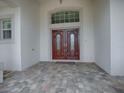 Elegant double front doors with glass accents, set on a stone tiled front porch at 1573 Blenheim Trl, The Villages, FL 32162