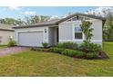Well-kept home showcasing a lush green lawn, mature landscaping, and a side-entry two-car garage at 28078 Poppy Ct, Leesburg, FL 34748