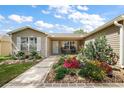 Inviting home exterior featuring a walkway leading to a cozy front porch with lush flowerbeds at 299 Jefferson Ln, The Villages, FL 32162
