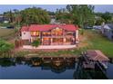 Beautiful aerial view of waterfront home with a red tile roof, lush landscaping, and private dock at 3011 Lake Woodward Dr, Eustis, FL 32726