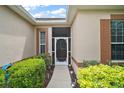 Front entryway with a decorative glass storm door surrounded by green bushes at 3828 Arbordale Ct, Leesburg, FL 34748