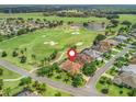 Aerial view showcases a home on a golf course with a pin; scenic community featuring lush greenery and a tranquil lake at 383 Kilmer Way, The Villages, FL 32162