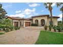 Charming Mediterranean home featuring a brick driveway, lush landscaping, and an arched entrance at 38716 Oak Place Ct, Lady Lake, FL 32159