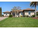 Charming single-story home showcasing lush landscaping and a well-manicured green lawn under a clear blue sky at 39505 Hillrise Ln, Lady Lake, FL 32159