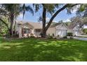 Attractive single-story home featuring a lush lawn, mature trees, and a brick-paved driveway to a two-car garage at 411 Loma Paseo Dr, The Villages, FL 32159