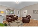 Inviting living room with hardwood floors, vaulted ceiling, and comfortable leather seating by the fireplace at 411 Loma Paseo Dr, The Villages, FL 32159