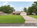 Well-maintained single-story home with a spacious front yard, mature trees, and a driveway leading to the garage at 4145 Dora Wood Dr, Mount Dora, FL 32757