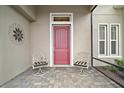 Inviting front porch with seating area showcasing a decorative metal art piece and striking red front door at 5195 Greens Dr, Lady Lake, FL 32159