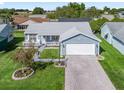 Aerial view of a well-kept single-story home featuring a manicured lawn and brick driveway at 530 Valencia Pl, The Villages, FL 32159