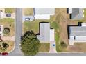 Aerial view of a well-maintained single-Gathering home with a brick driveway, surrounded by lush landscaping in a quiet neighborhood at 705 Prado Dr, The Villages, FL 32159