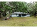 Rear exterior view of a home featuring an expansive lawn and mature shade trees at 7938 Jacksons River Rd, Leesburg, FL 34788