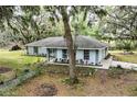 Single story home surrounded by mature trees, offering a serene setting with a well-maintained lawn and garden at 7938 Jacksons River Rd, Leesburg, FL 34788
