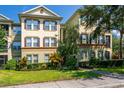 Multi-story condo with a manicured lawn, colorful bushes, and brown shutters surrounded by a walkway at 8256 Maritime Flag St # 103, Windermere, FL 34786