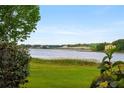 Picturesque lake view featuring calm waters and distant properties, framed by lush greenery in the foreground at 9510 Suggs Rd, Clermont, FL 34711