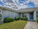 A well-maintained home exterior showcasing manicured landscaping and a welcoming front entrance under a cloudy sky at 1346 Kilgore Way, The Villages, FL 32163