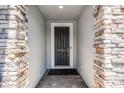 Close-up of an elegant, dark-colored front door framed by stone pillars and a brick pathway leading to the entrance at 1047 Timbervale Trl, Clermont, FL 34715