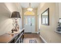 Bright entryway features a decorative chandelier, stylish console table, and wood-look floors at 1222 Camero Dr, The Villages, FL 32159