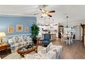 Bright living room featuring an open floor plan, wood floors, and a view into the kitchen and dining area at 1526 Blueberry Way, The Villages, FL 32162