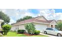 Side exterior featuring manicured lawn, attached two-car garage and mature cactus at 15702 Bay Vista Dr, Clermont, FL 34714
